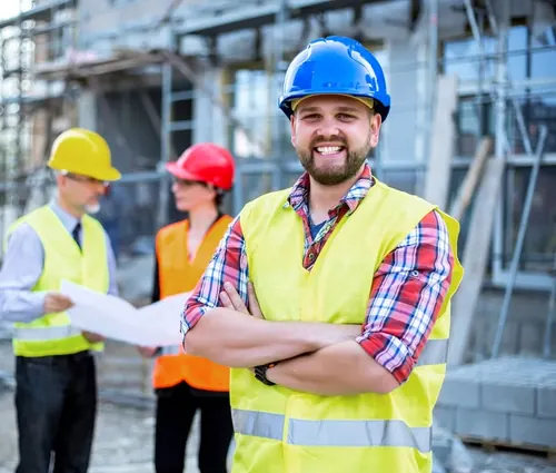 General contractor site team in hard hats and safety vests reviewing plans on a commercial job site